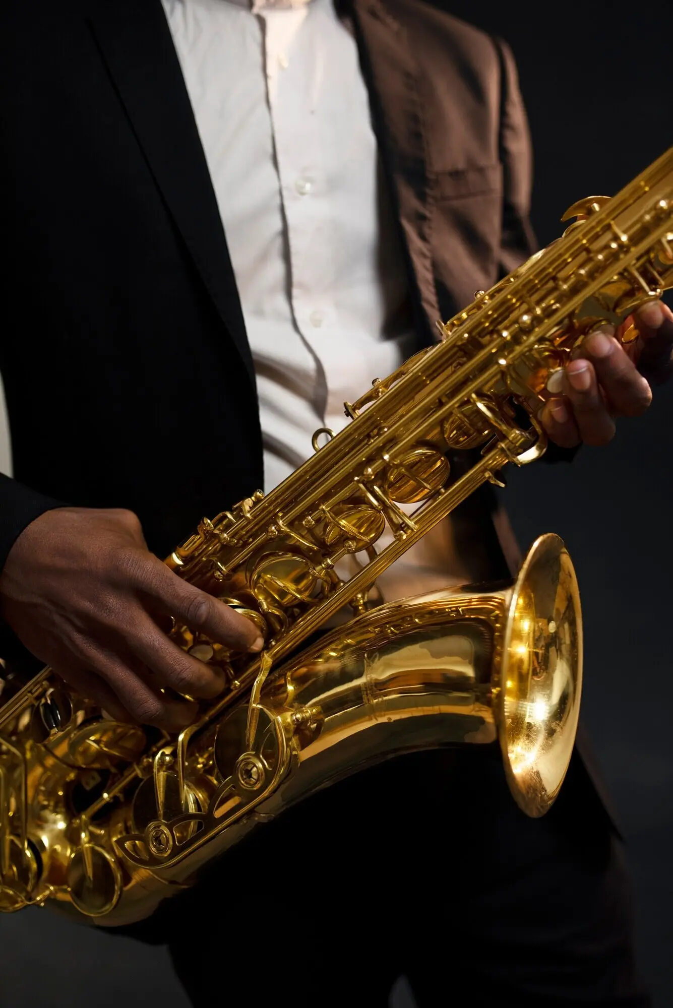 Nahaufnahme eines Musikers im Anzug, der ein Saxophon hält.